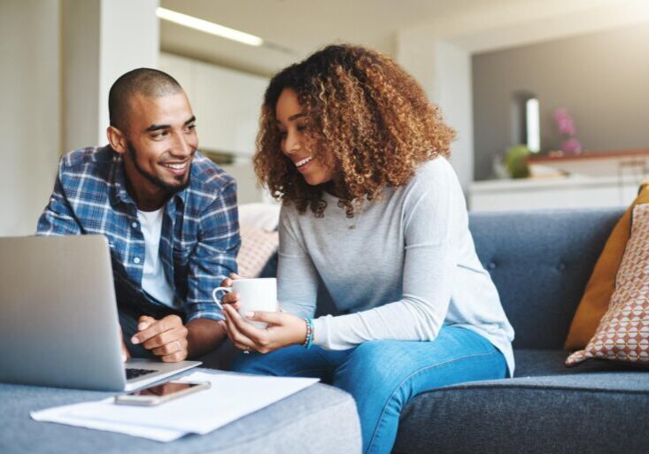Happy couple discussing finances while looking at laptop
