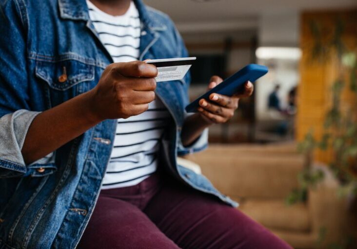 Woman holding phone and debit card.